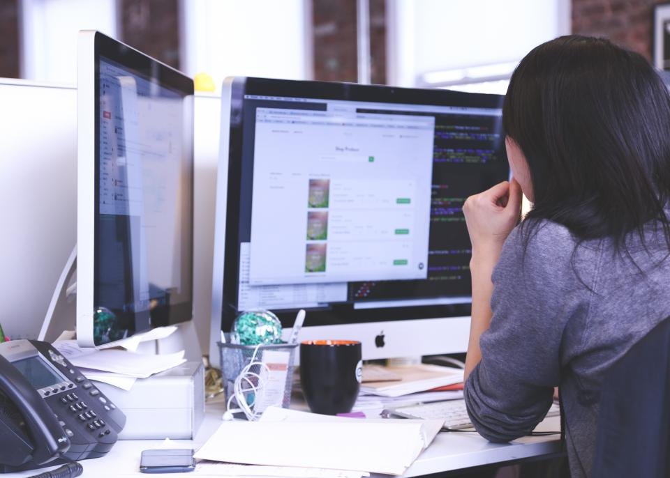 Professional working with CRM data across desktop monitors in an office